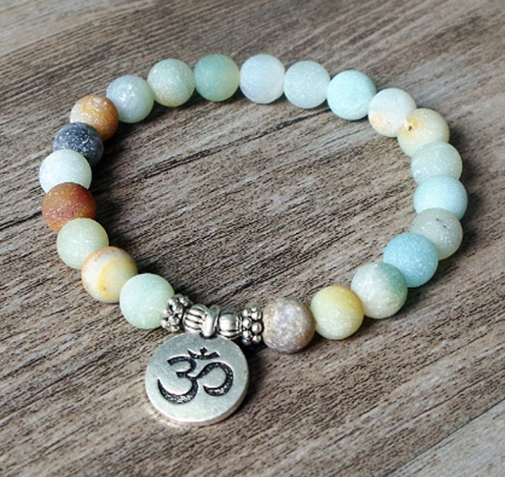 Beaded bracelet with an Om charm on a wooden surface