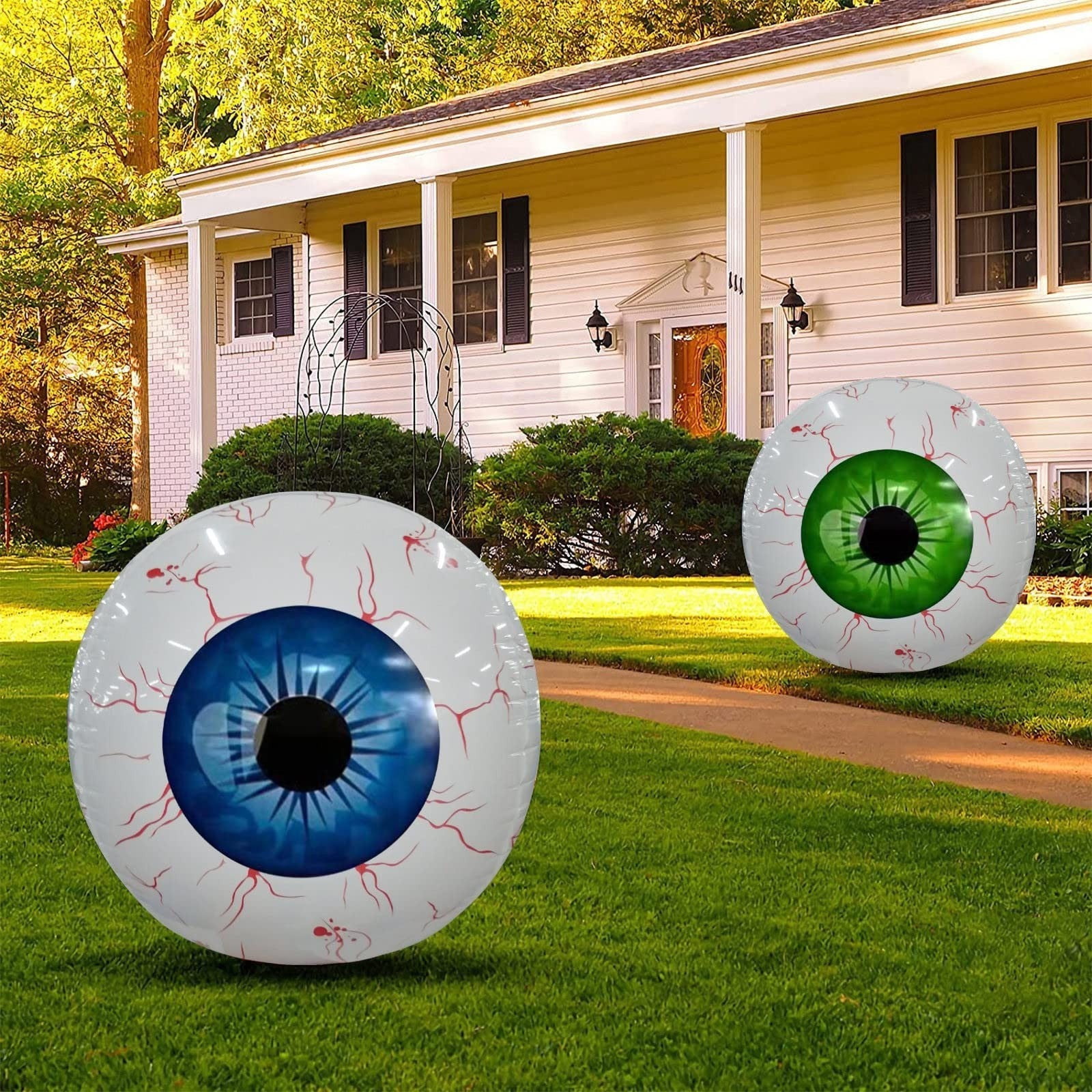 Two inflatable eye decorations on a lawn in front of a house.