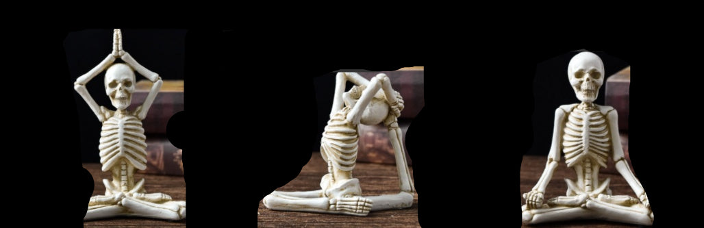 Three skeleton figures in yoga poses with measurements on a wooden surface.