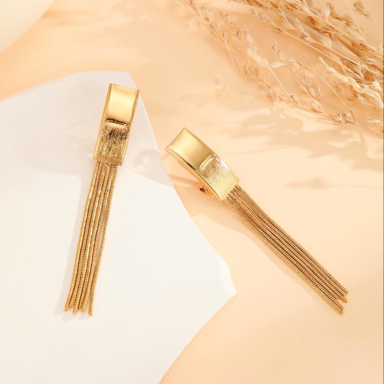 Gold hair clips with tassels on a light background