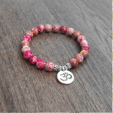 Beaded bracelet with Om charm on a wooden surface