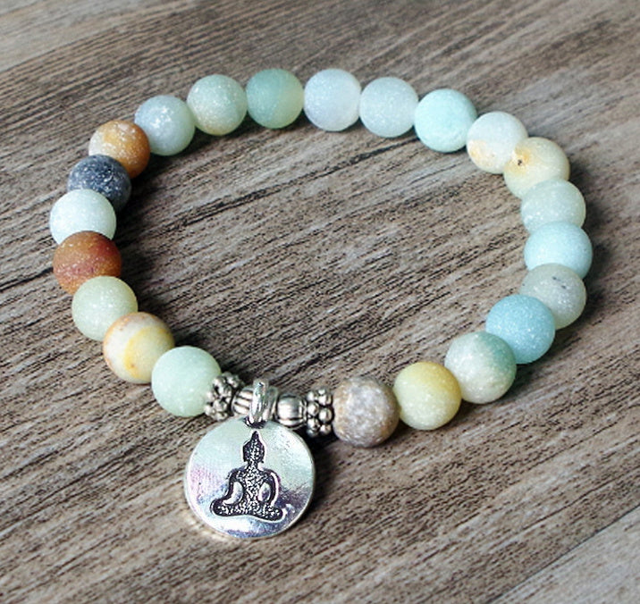 Beaded bracelet with a Buddha charm on a wooden surface