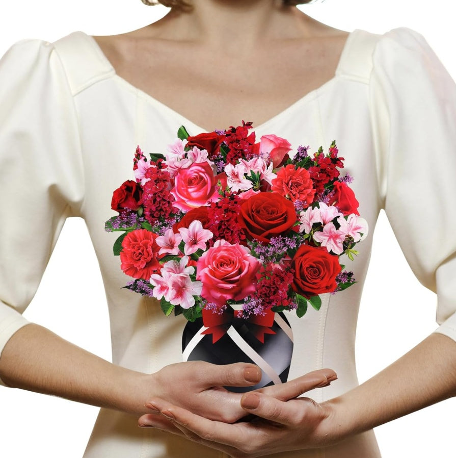 Person holding a bouquet of red and pink flowers in front of a white background