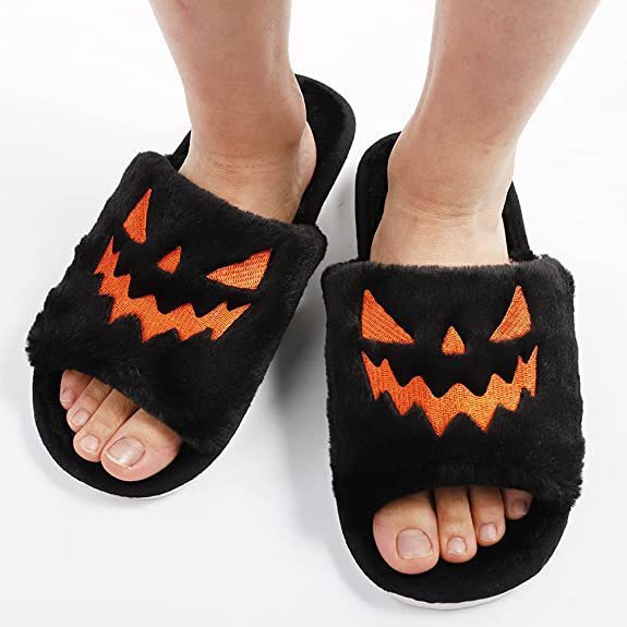 Black slippers with jack-o'-lantern faces on a white background