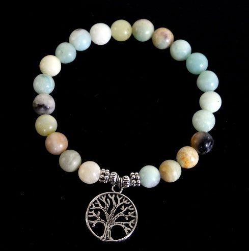 Bracelet with multicolored beads and a silver tree of life charm on a black background