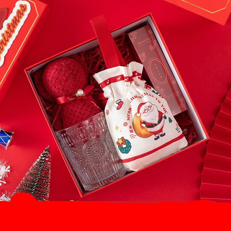 Gift set with red bear towel, glass, and Christmas-themed bag on a red background