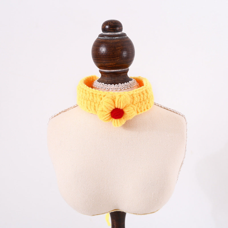 Yellow knitted collar with a red flower on a mannequin bust against a white background