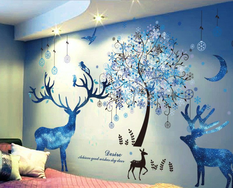 Wall decal of deer and a tree with decorative elements on a blue wall.