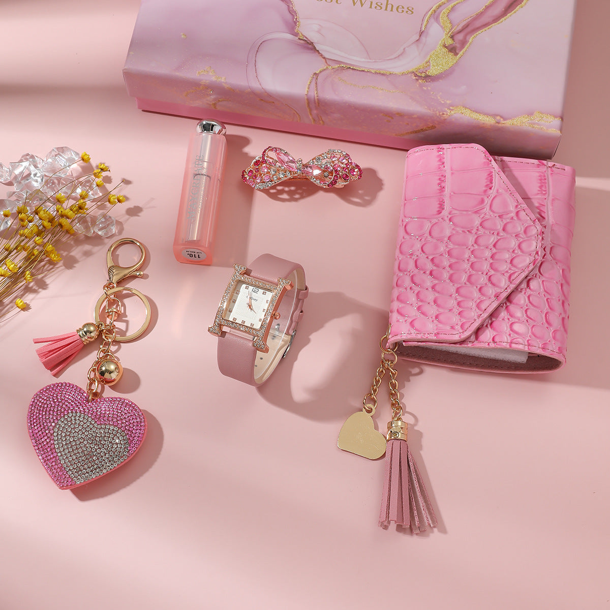Pink accessories including a keychain, watch, and wallet on a pink background