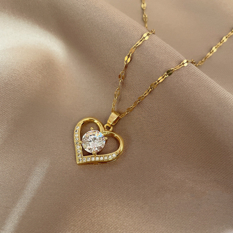 Gold heart-shaped necklace with a diamond pendant on a beige fabric background