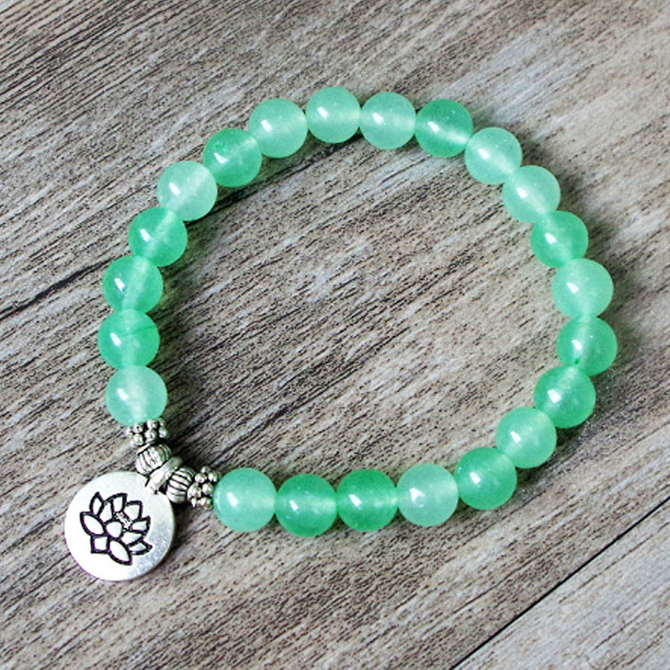 Green beaded bracelet with a silver charm on a wooden surface