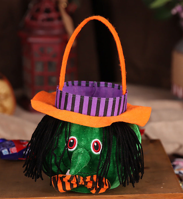 Halloween-themed candy basket with green body, orange hat, and purple band on a wooden surface.