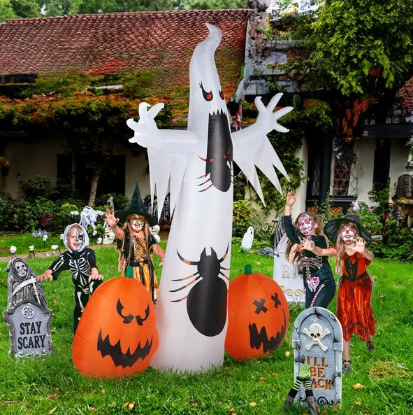 Halloween decorations including inflatable ghost, pumpkins, and children in costumes on a grassy lawn.