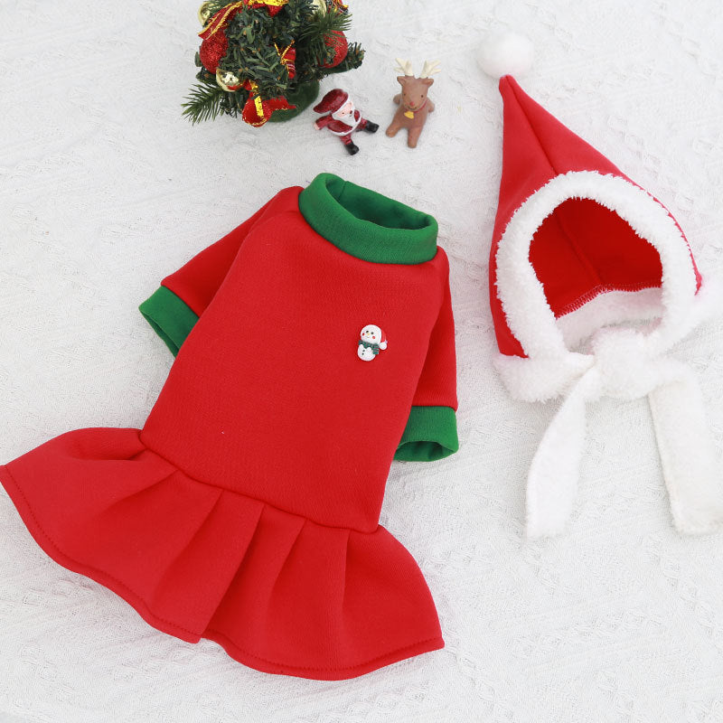 Red pet dress with green trim and a Santa hat on a white background