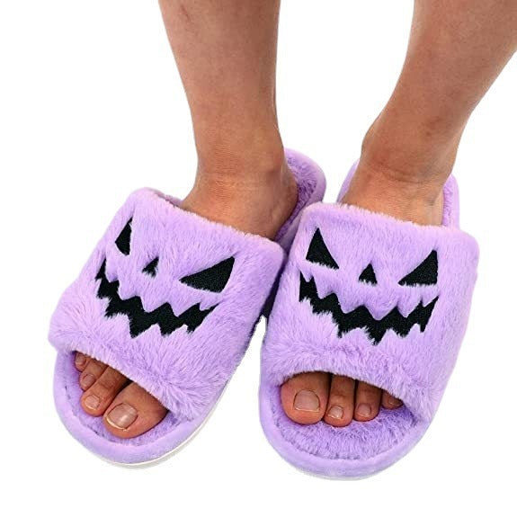 Purple slippers with pumpkin face design on a white background