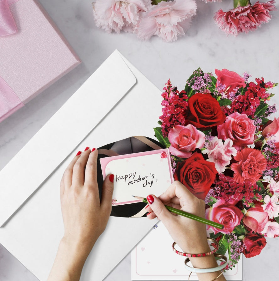 Bouquet of flowers and a card with 'Happy Mother's Day!' on a marble surface.