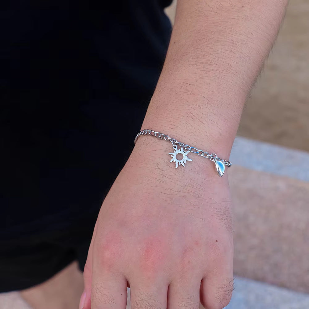 Silver bracelet with a sun charm on a wrist against a blurred background