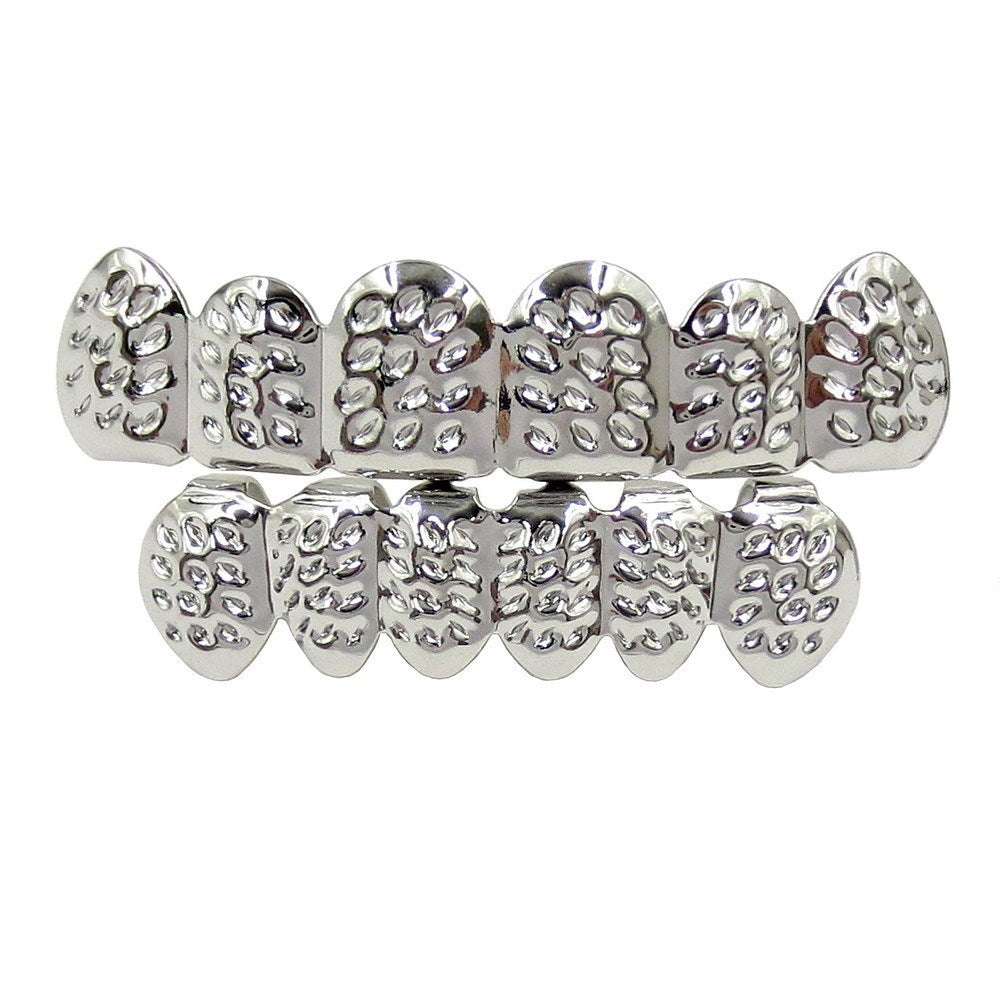 Silver dental grill with leaf-like patterns on a white background