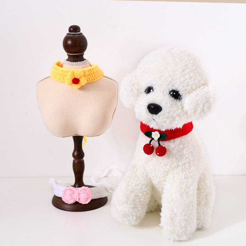 White dog wearing a red collar with floral decorations next to a mannequin with yellow and pink collars on a white background.