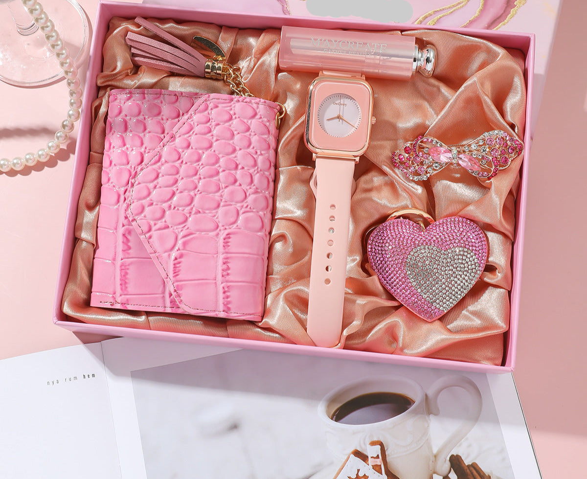 Pink gift set with phone case, watch, and heart-shaped item in a decorative box.