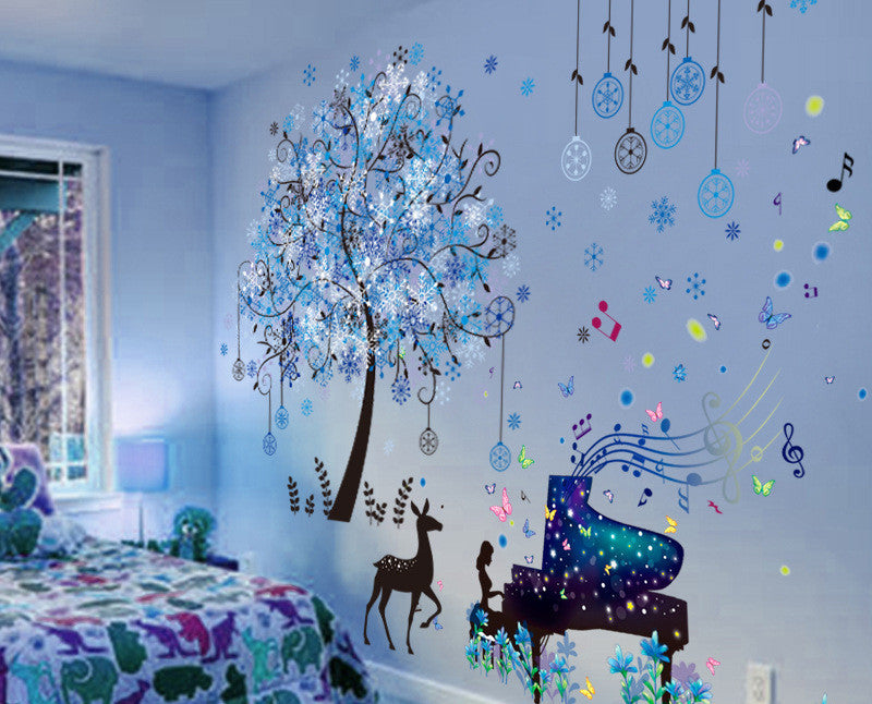 Decorative wall stickers of a tree, deer, piano, and musical notes on a light blue wall.