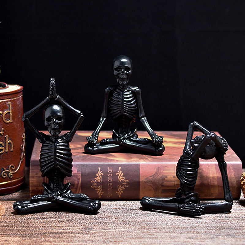 Three black skeleton figurines in various poses on a wooden surface with a dark background.