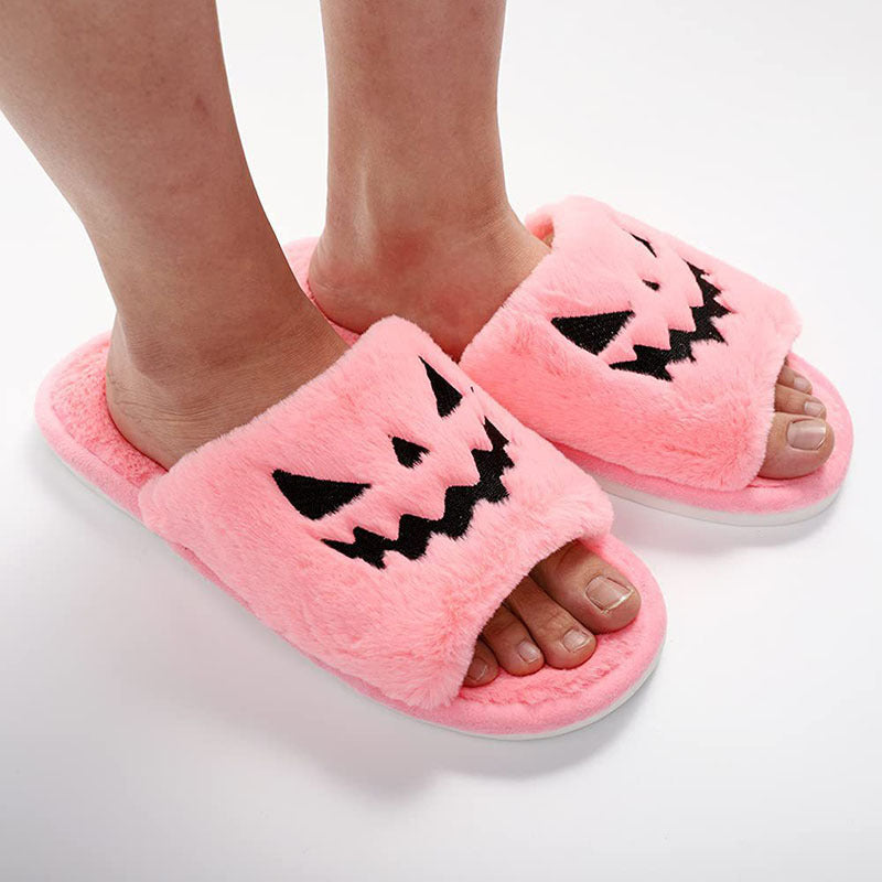 Pink slippers with jack-o'-lantern faces on a white background