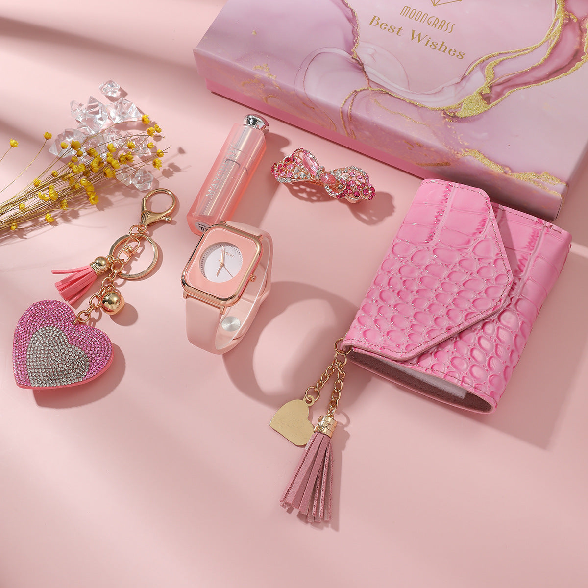 Pink accessories including a watch, wallet, and keychain on a pink background