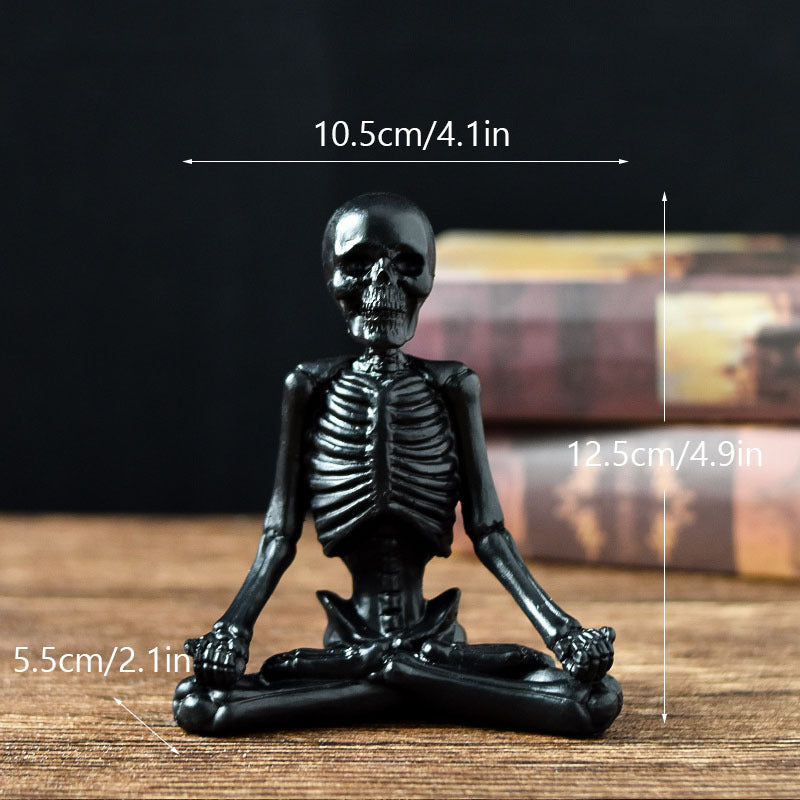 Black skeleton figurine sitting in lotus position with measurements on a wooden surface.