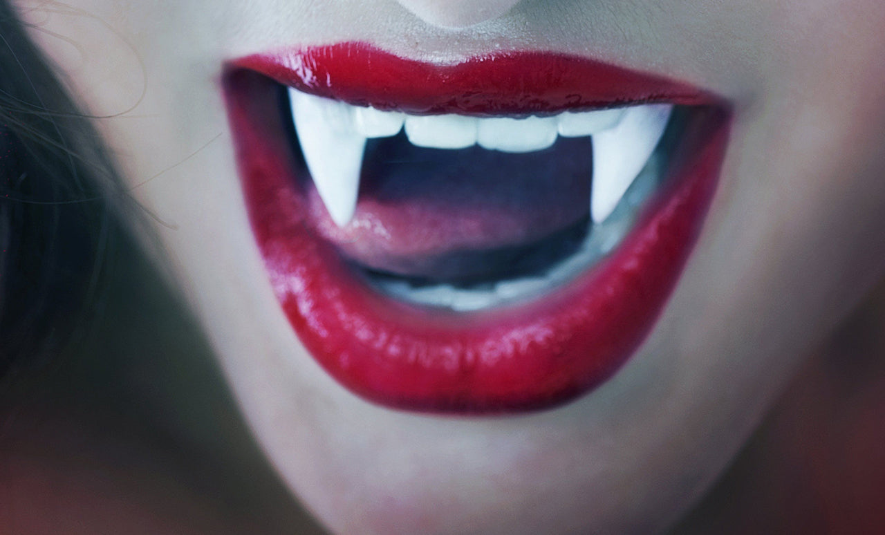 Close-up of a person with red lipstick and fangs.