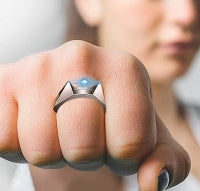Close-up of a hand wearing a ring with a blue gemstone.
